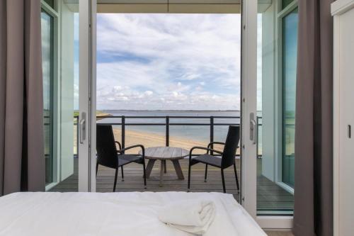 a bedroom with a bed and a view of the beach at Vakantiewoning aan het water - met 2 balkons - Vista Maris - Nr 38 in Sint Annaland