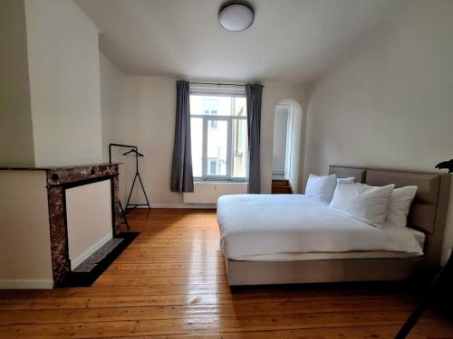 a bedroom with a white bed and a window at La Suite Alice in Brussels