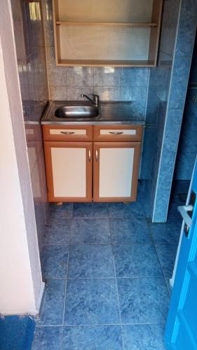 a small kitchen with a sink and a tiled floor at City Rooms 400m from Center in Mitrovicë