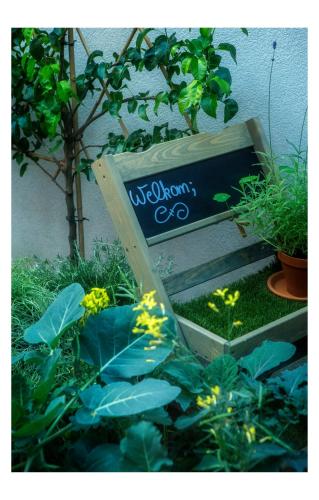 a sign in a garden with plants and flowers at Hotel Restaurant Vous lé Vous in Hasselt