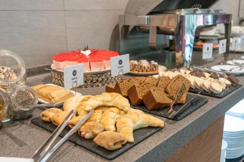 a buffet line with bread and pastries and a cake at abba Presidente Suites Santiago in Santiago