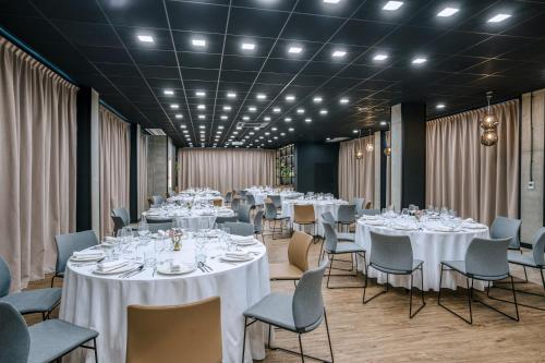 a room with tables and chairs with white tablecloths at Hyatt Place Krakow in Kraków