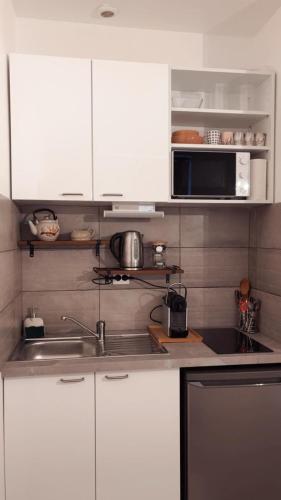 une cuisine avec des armoires blanches, un évier et un micro-ondes dans l'établissement Le Havre Nantais, à Nantes