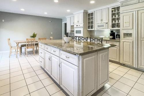 a kitchen with white cabinets and a dining room with a table at Akasa in Stratford