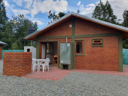 a small red brick house with a table and chairs at Los Colibríes in Lago Puelo