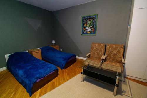 a bedroom with two beds and a chair and a painting at Apartament Suwałki Centrum Wesoła in Suwałki
