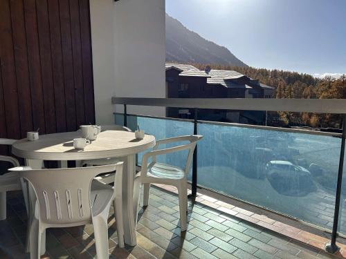 une table blanche et des chaises sur un balcon avec vue dans l'établissement Studio montagne 4 pers. avec balcon, pistes à 100m, parking, local à skis - Montgenèvre - FR-1-330D-77, à Montgenèvre