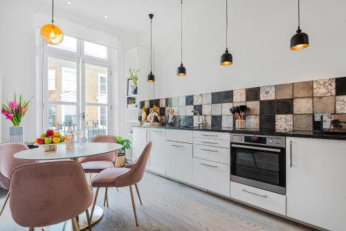 a white kitchen with a table and chairs at Lady on the Lane- 2 bed Primrose Hill in London