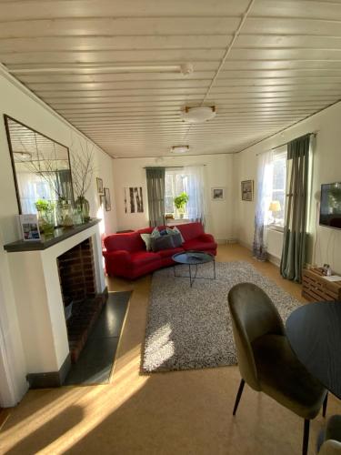 a living room with a red couch and a fireplace at Snöå Bruk Hotell och konferens in Dala-Järna