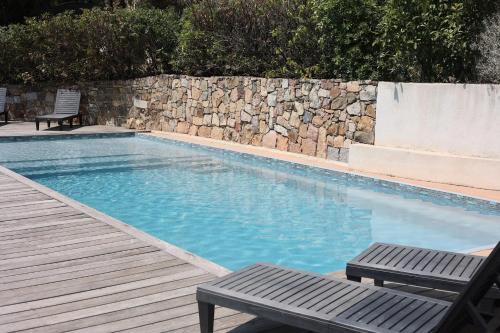 a swimming pool with a bench and a stone wall at La Villa in Favone
