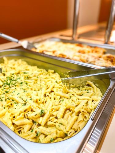 a tray of macaroni and cheese with a spatula at Hotel Zata - Econômico in Criciúma