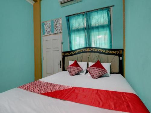 a bedroom with a bed with red and white pillows at Hotel O Rania Kost Simpang Rimbo in Jambi