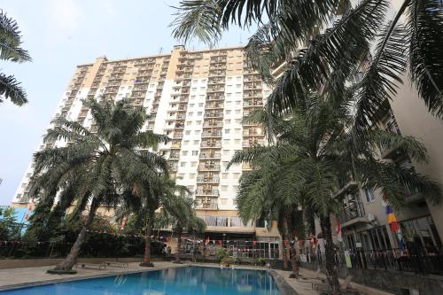 a large building with palm trees in front of it at Apartemen Mutiara Bekasi by Alfa Rooms in Pekayon Satu