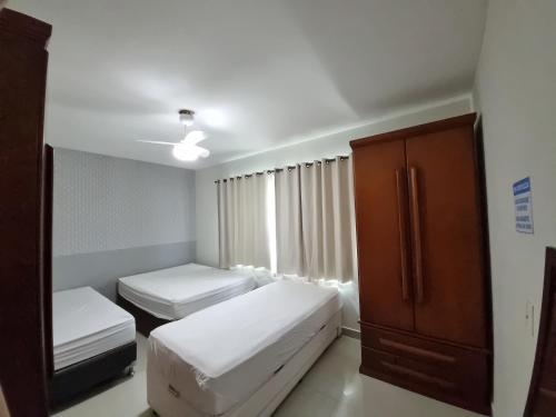 a small room with two beds and a cabinet at Casa de praia no Peró Cabo Frio com Piscina e Hidromassagem in Cabo Frio