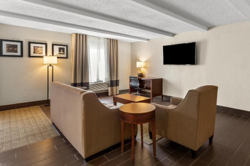 a hotel room with a couch and a table and a television at Comfort Inn St Louis - Westport Event Center in Maryland Heights