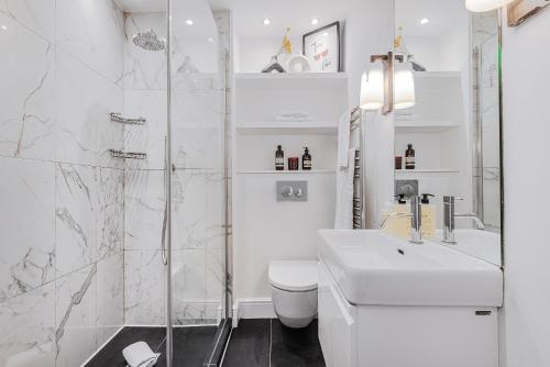 a white bathroom with a toilet and a shower at Lady on the Lane- 2 bed Primrose Hill in London