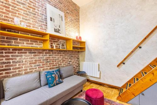 un salon avec un canapé et un mur de briques dans l'établissement GuestReady - Elegant Comfort Near the Metro, à Paris