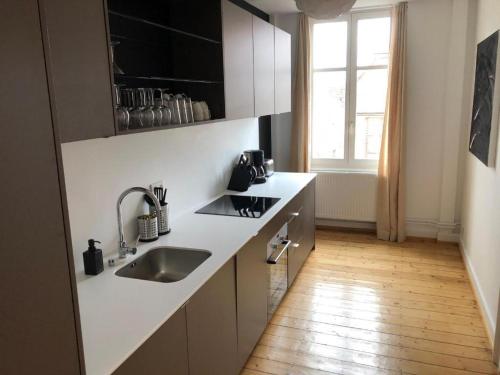 a kitchen with white counters and a sink and a window at PRALINE in Colmar