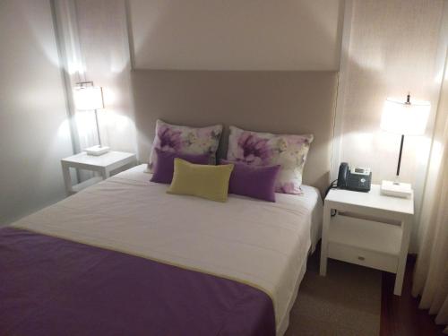 a bedroom with a large bed with purple and yellow pillows at Monsanto GeoHotel Escola in Monsanto