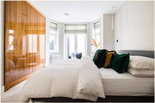 ein Schlafzimmer mit einem großen Bett mit weißer Bettwäsche und grünen Kissen in der Unterkunft Home Sweet Hampstead Heath in London