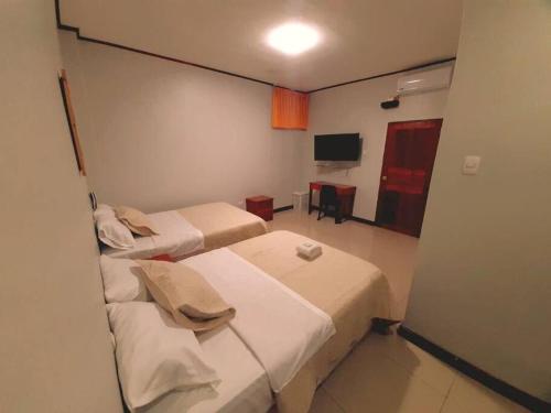 a hotel room with two beds and a television at Apartamento 300 Tercer piso,cómodo ,amplio,privado in Iquitos