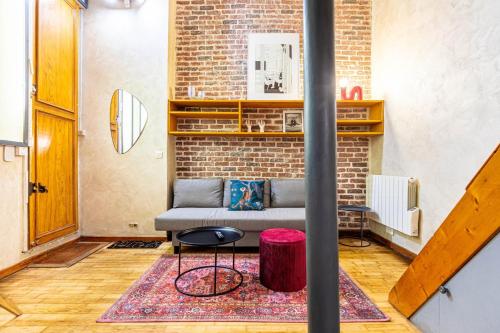 un salon avec un canapé et un mur de briques dans l'établissement GuestReady - Elegant Comfort Near the Metro, à Paris