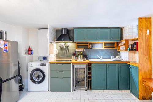 - une cuisine avec des placards verts et un lave-linge/sèche-linge dans l'établissement GuestReady - Elegant Comfort Near the Metro, à Paris
