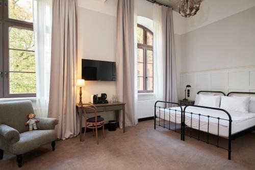 a bedroom with a bed and a chair and a desk at ARCHE Klasztor Wrocław in Wrocław