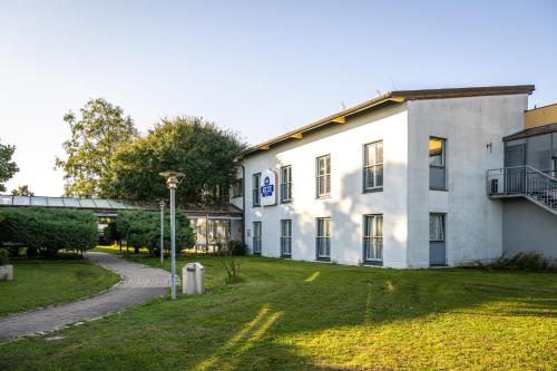 a white building with a grass yard next to a road at Dresdner Tor Süd in Wilsdruff