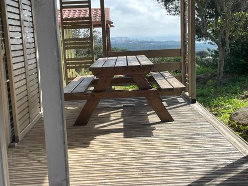 a wooden bench sitting on a porch with a chair at Camping Trinité in Bonifacio