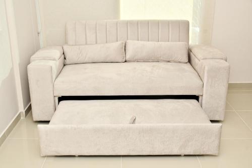 a living room with a couch and a ottoman at Excelente ubicación, cómodo apartamento in Barranquilla