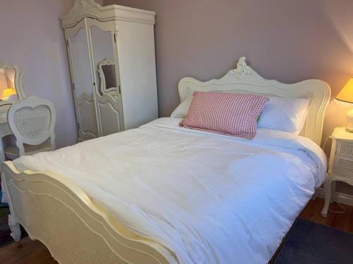 a white bed with a pink pillow on top of it at LILY'S LODGE - Beautiful Central Buncrana Home in Buncrana