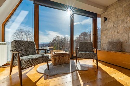 a living room with two chairs and a large window at Vila Sun forest in Žabljak