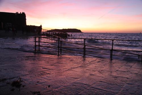 a sunset over the ocean with a fence on the beach at Hotel des Abers in Saint Malo
