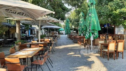 un grupo de mesas y sillas con sombrillas verdes en HOTEL ROOM CITY SQUARE with great VIEW no parking, en Skopje