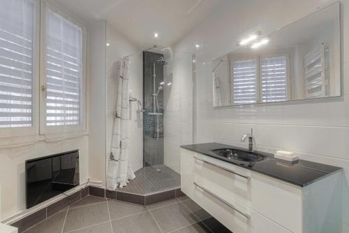une salle de bain blanche avec une douche et un lavabo dans l'établissement Spacieux et Charmant 150m2 Place Maréchal Lyautey, à Lyon
