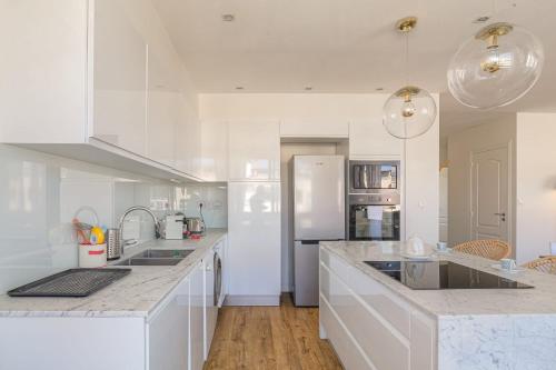 une cuisine avec des placards blancs et un grand comptoir dans l'établissement Charmant et Spacieux avec vue à 1 min de Tête d'Or, à Lyon