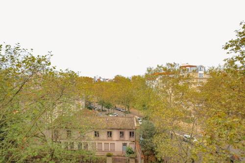 un bâtiment sur le côté d'une colline plantée d'arbres dans l'établissement Charmant et Chaleureux proche Tête d'Or, à Villeurbanne