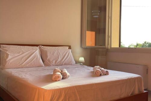 two pairs of slippers on a bed with a window at West Sicily - Villa with Garden and Parking in Marsala