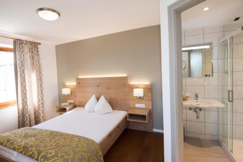 a hotel room with a bed and a bathroom at Logis Auberge Du Mehrbachel - Hôtel & Restaurant in Saint-Amarin