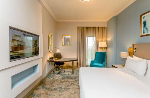 a hotel room with a bed and a desk and a tv at Southern Sun Sandton in Johannesburg