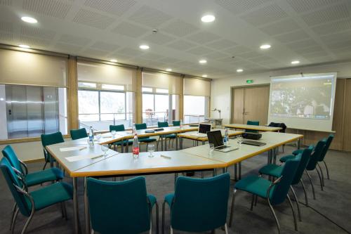 a conference room with tables and chairs and a screen at Logis Auberge Du Mehrbachel - Hôtel & Restaurant in Saint-Amarin