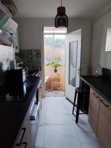 une cuisine avec des comptoirs noirs et une porte donnant sur une terrasse. dans l'établissement Le tropical 2 chambres, à Romans-sur-Isère