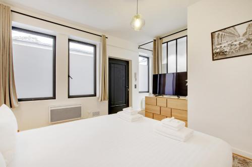 - une chambre blanche avec un grand lit et des fenêtres dans l'établissement Pick A Flat's Apartment in Place Vendôme - Rue Saint-Honore, à Paris