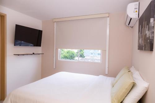 a bedroom with a white bed and a window at Excelente ubicación, cómodo apartamento in Barranquilla