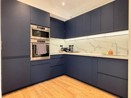 La cuisine est équipée de placards bleus, d'une cuisinière et d'un évier. dans l'établissement Renovated Apartment near Tuileries and Concorde, à Paris