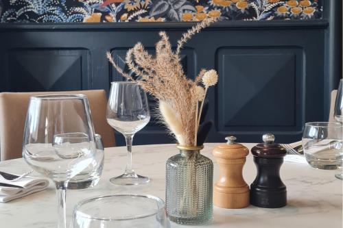 a table with wine glasses and a vase with dried flowers at Kyriad Vannes Centre Ville in Vannes