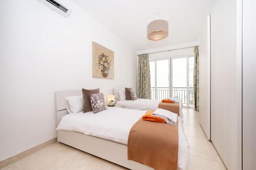 a white bedroom with two beds and a window at Hillock Residence Apartments in Marsalforn