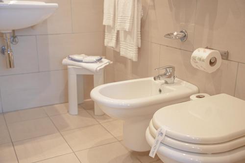 a white bathroom with a toilet and a sink at Hotel Europa in Reggio Emilia