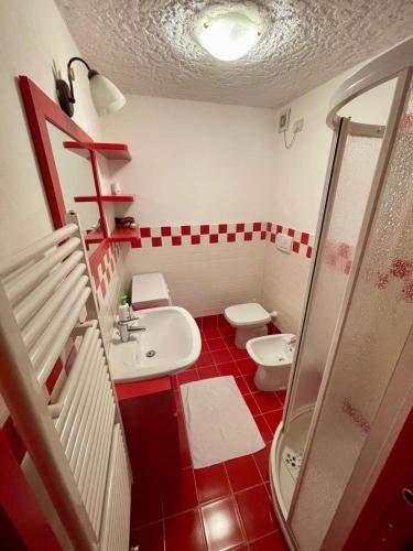 a red and white bathroom with a toilet and a sink at Casa Lilly in Folgarida